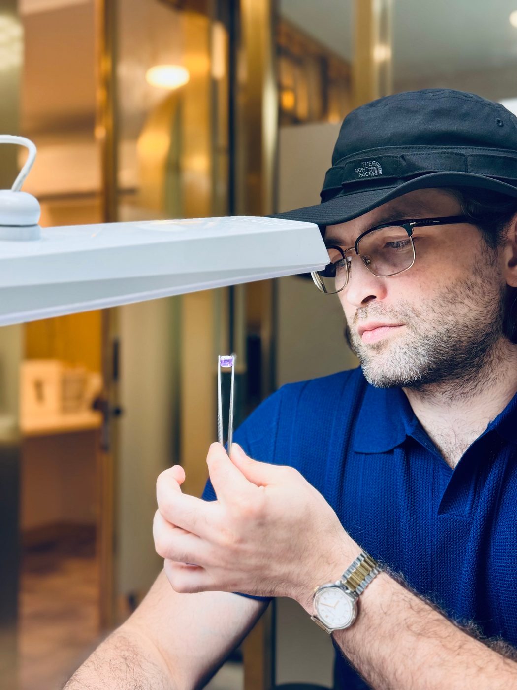 Examining a stone in tweezers under the lamp