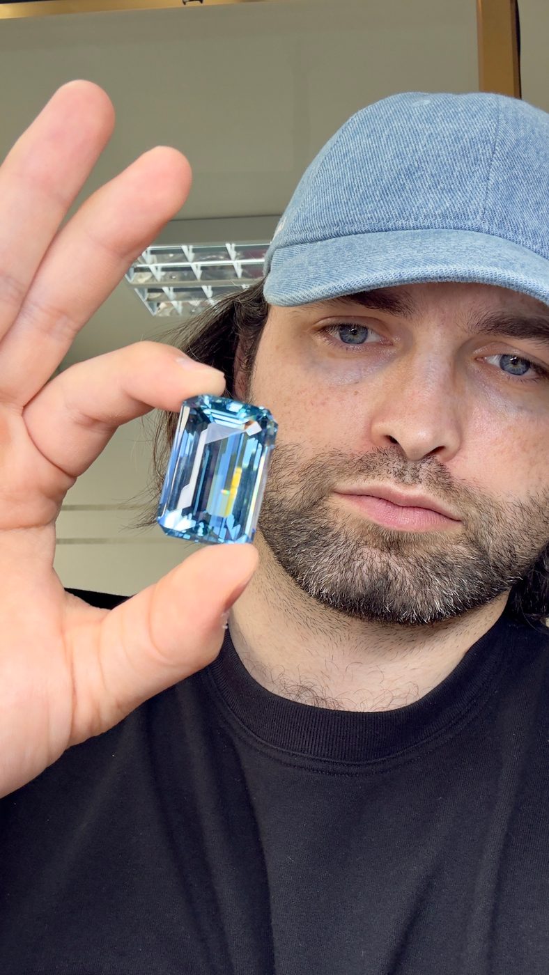 Holding a large blue emerald-cut stone