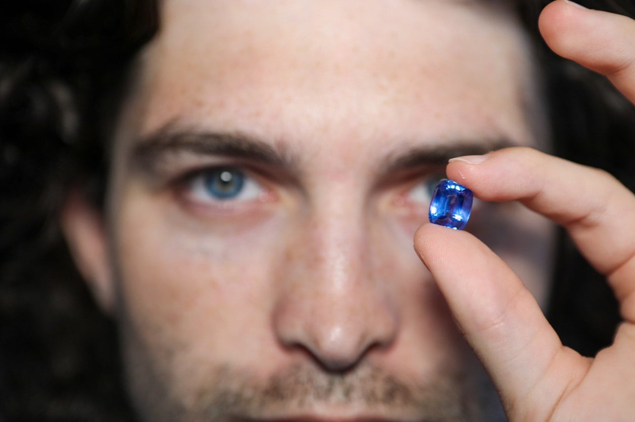 Lambert Vissot examining a blue sapphire held up to his eye